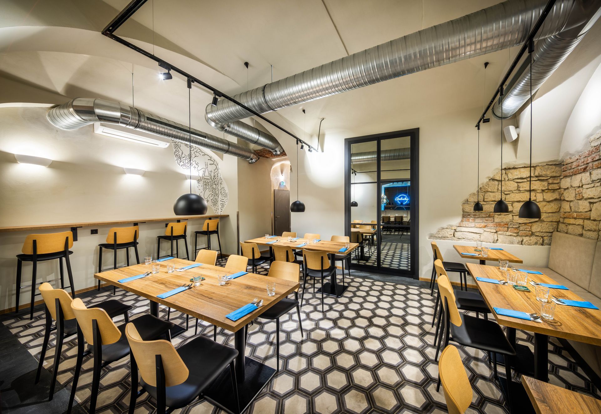 Restaurace se stoly a židlemi a cihlovou zdí.