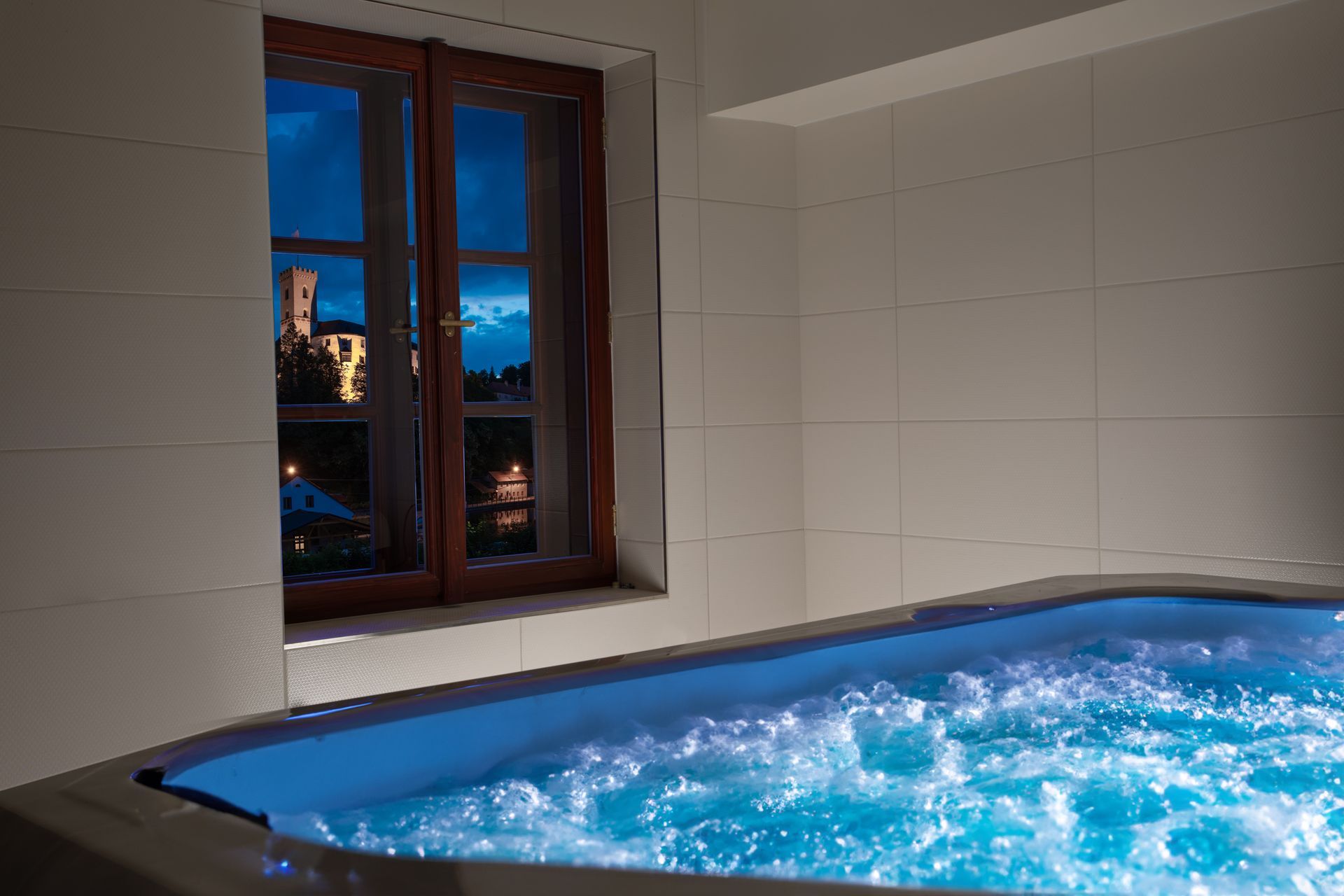 Uprostřed místnosti s oknem je jacuzzi.