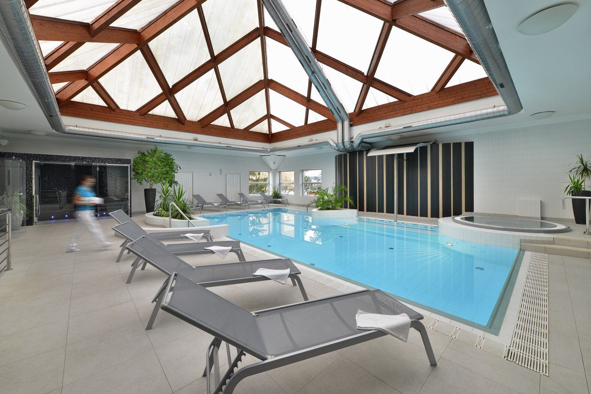 Velký krytý bazén s lehátky a jacuzzi.