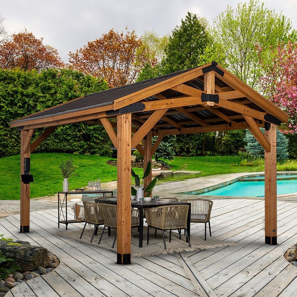 Wooden gazebo over a patio dining set beside a backyard swimming pool and landscaped garden.
