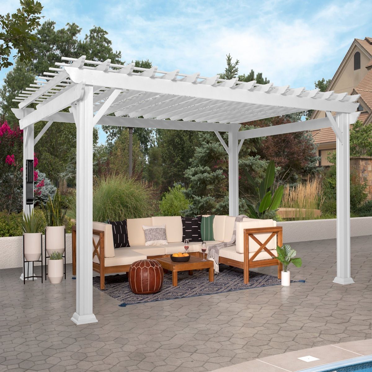 White pergola over outdoor patio seating with beige cushions, wooden coffee table, and potted plants