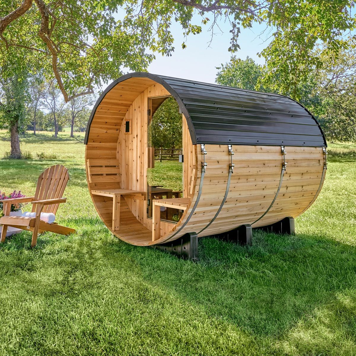 Wooden barrel-shaped outdoor sauna on grass with open front and bench seating