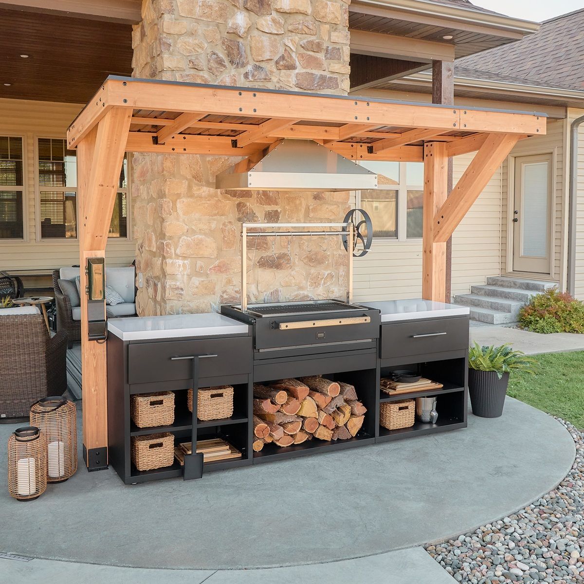 Outdoor patio kitchen with stone fireplace, wood pergola, and grill station with storage cabinets
