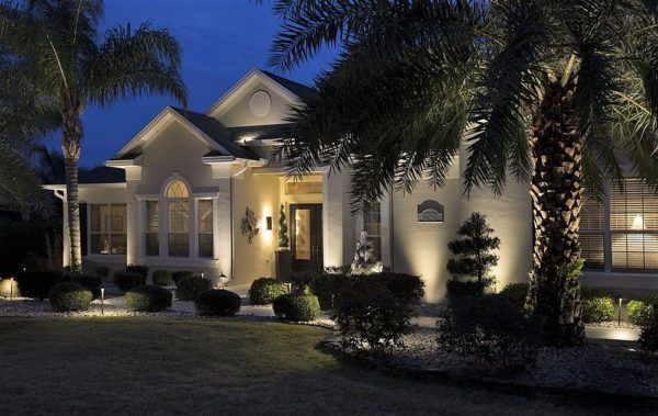 Illuminated luxury house at night with palm trees and landscaped front yard