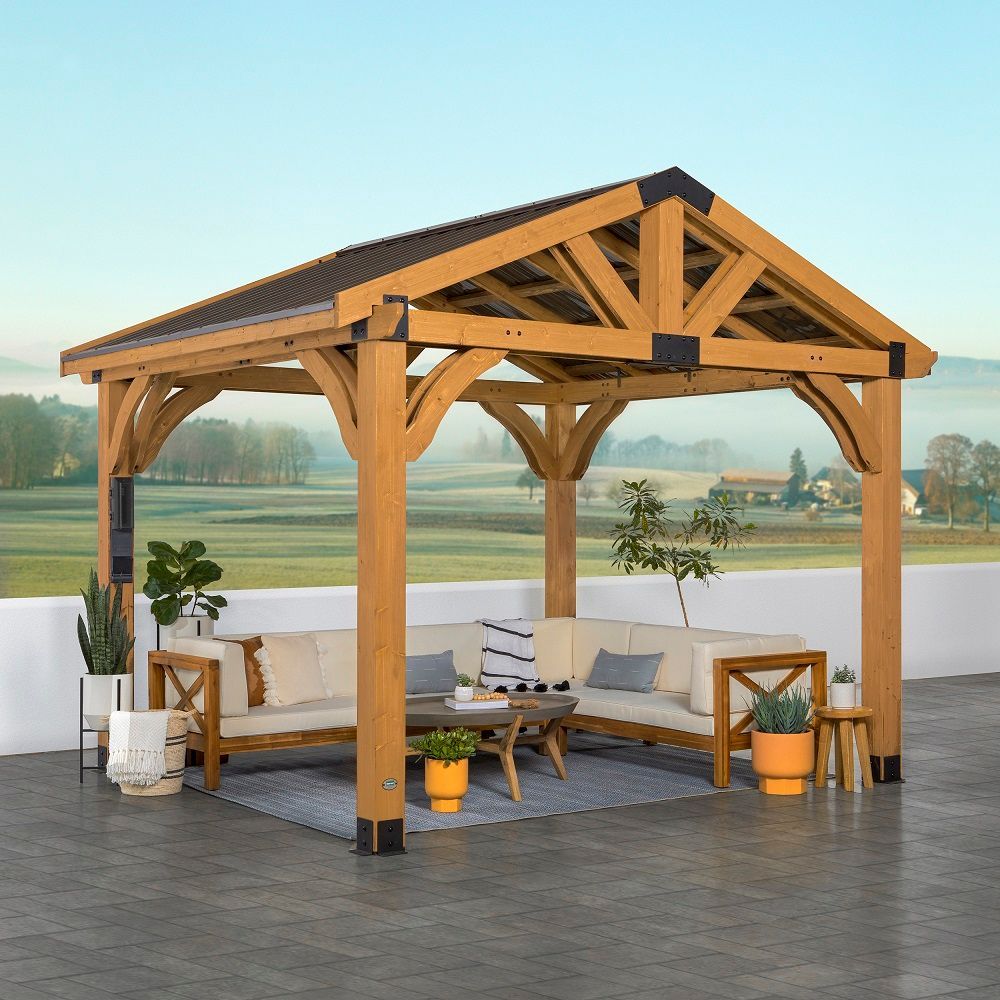 Wooden outdoor gazebo with cushioned seating on a patio overlooking a landscape.