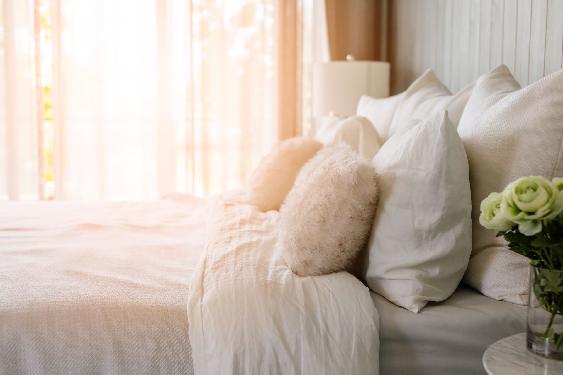 A welcoming guest bedroom with layered drapery at the windows and ample cozy bedding