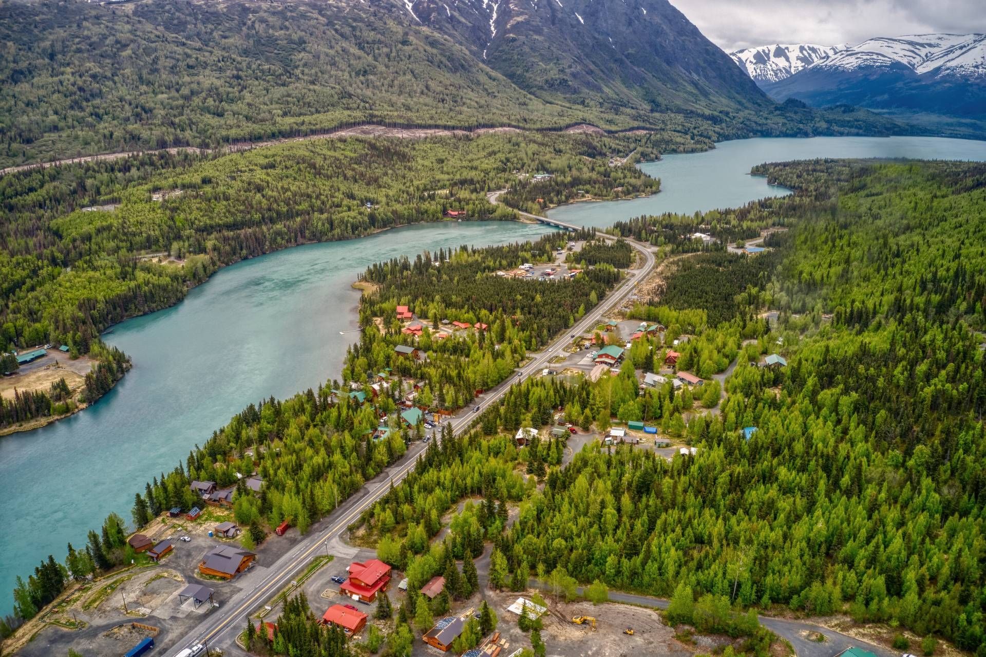 An aerial image of Cooper Landing, Alaska, with mountains, the Kenai River, and residences throughout