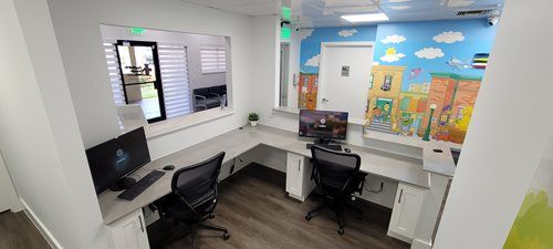 Office reception area with two workstations, Sesame Street mural on the wall.