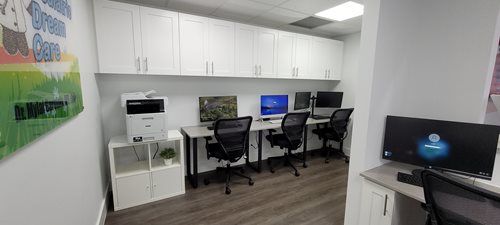 An office with computers, cabinets, desks, and chairs, and a printer.
