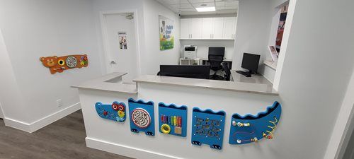 Reception area of a children's medical office with a play area and various wall decorations.