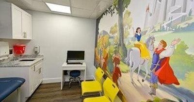 Doctor's exam room with a fairy tale mural and yellow chairs.