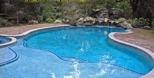 A large swimming pool with a waterfall in the backyard.