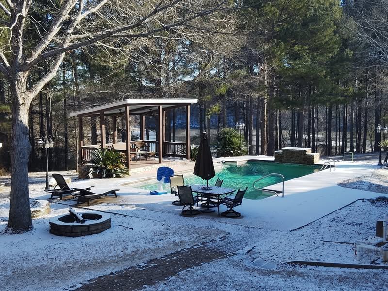 A swimming pool with a table and chairs in the snow