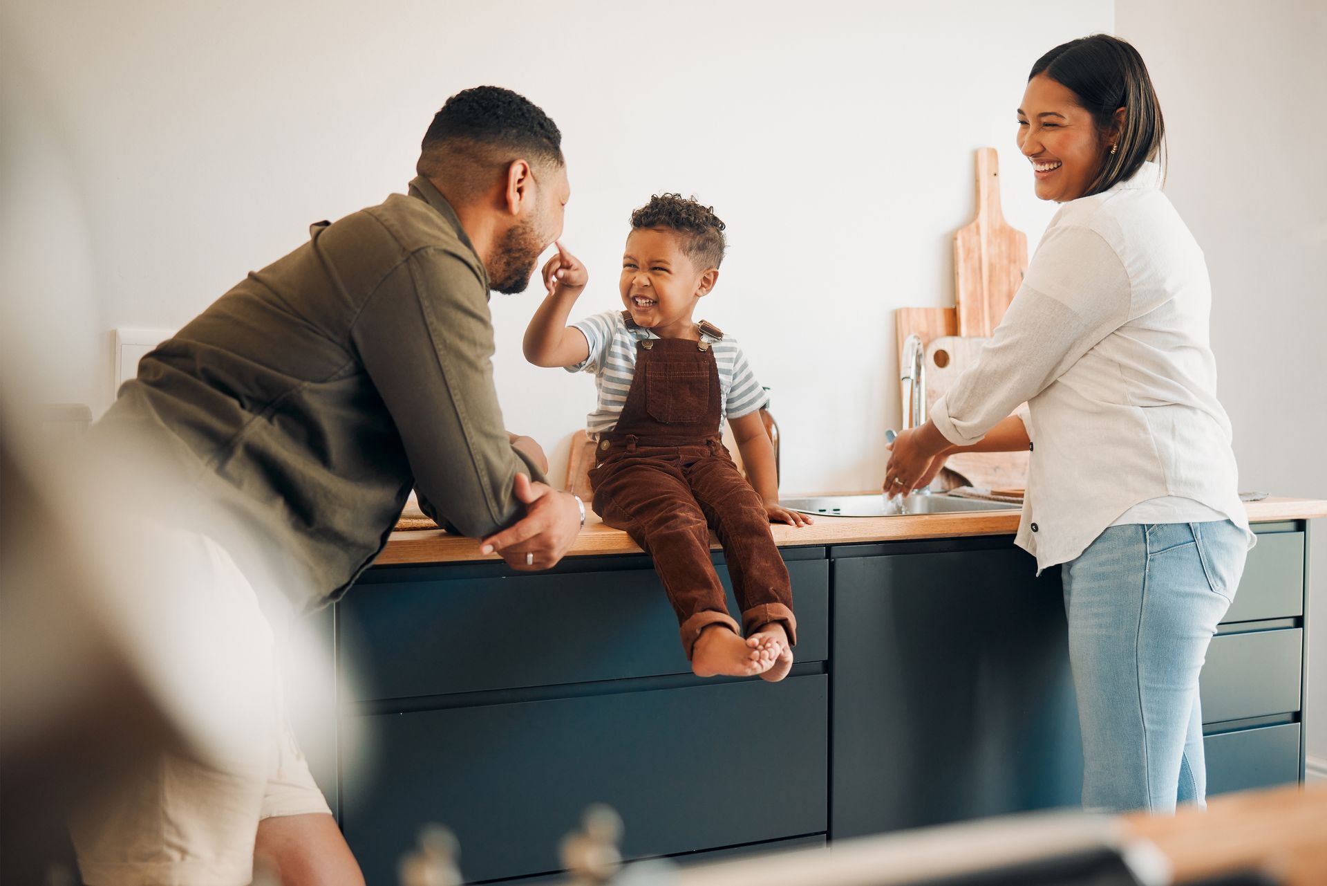 Family smiling at a reception desk, with a child sitting on the counter as two adults talk nearby