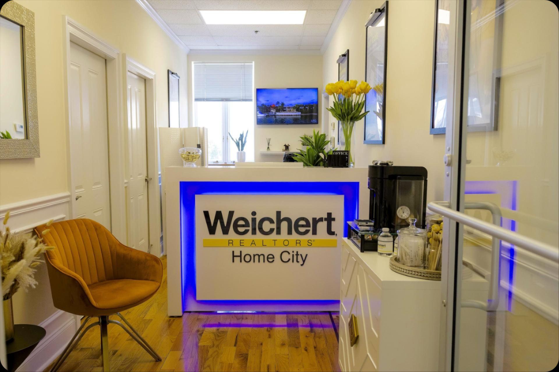 A waiting room with a chair and a sign that says welchert realty home city.