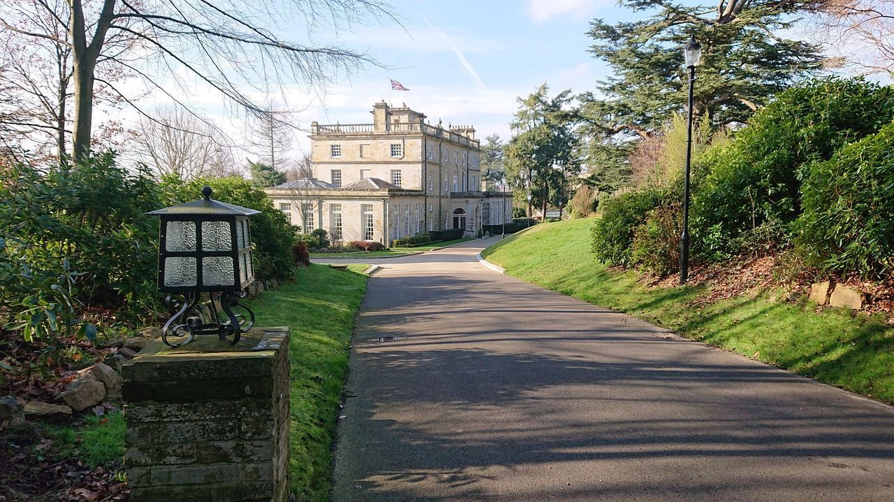A road leading to a large house with a lantern on the side of it.