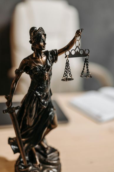 Bronze Lady Justice statue holding balanced scales on a desk