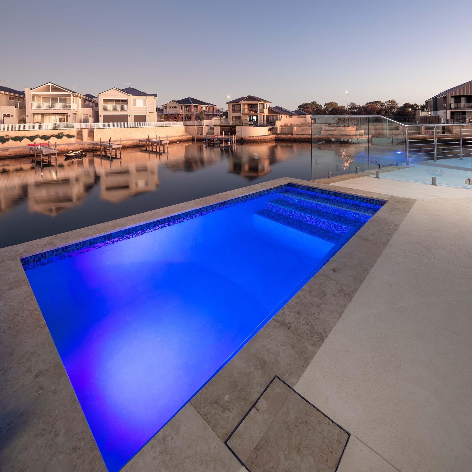 A large swimming pool is lit up with blue lights