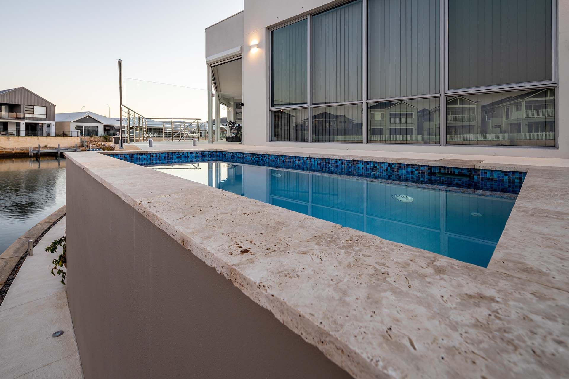 There is a large swimming pool in front of a house.