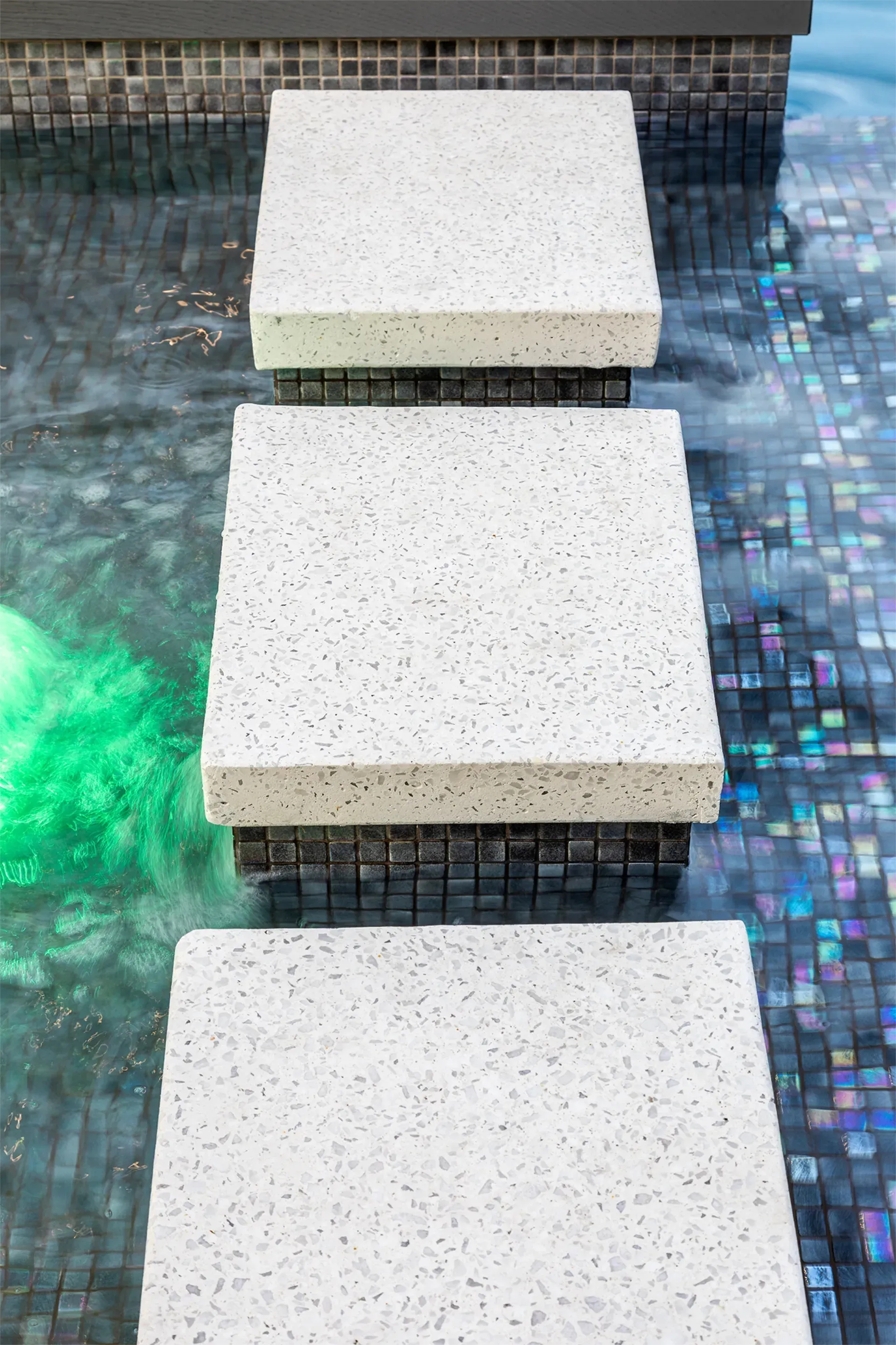 A row of white steps leading into a swimming pool.