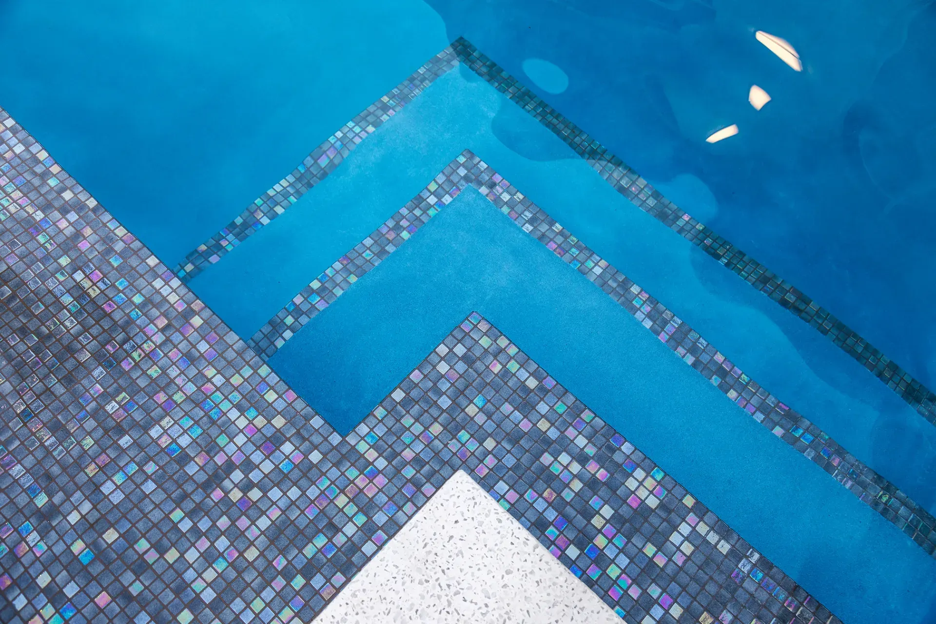 A swimming pool with blue tiles on the floor and stairs