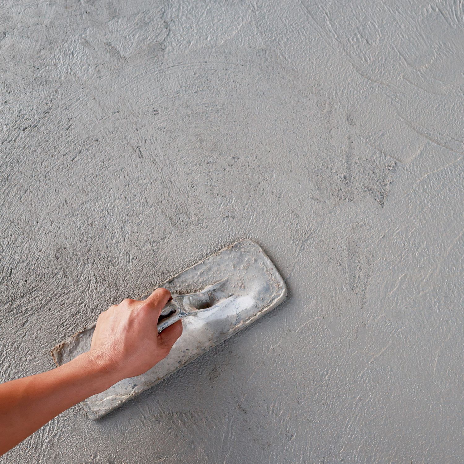 A person is plastering a wall with a trowel.