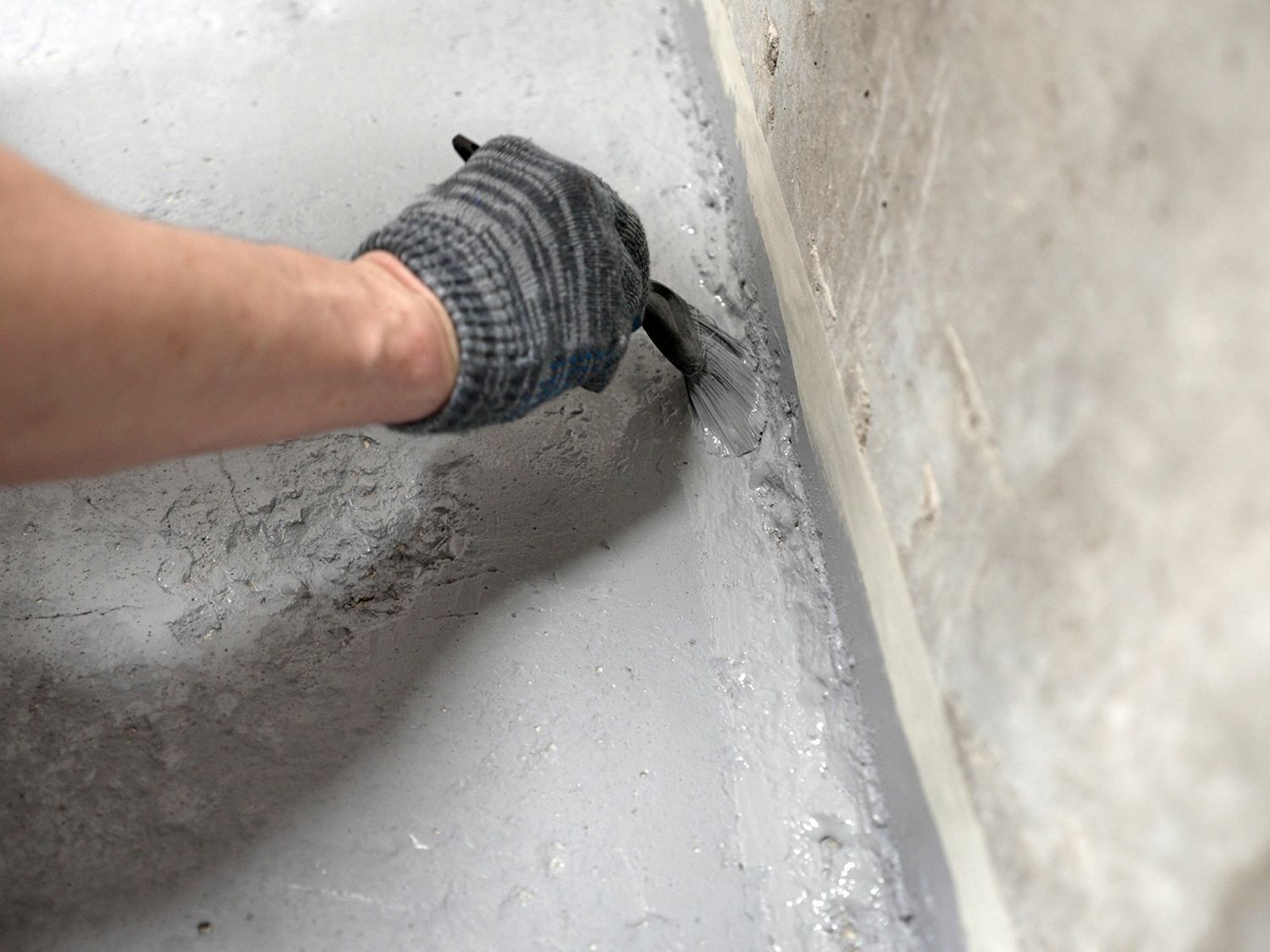 A person is painting a wall with a brush.