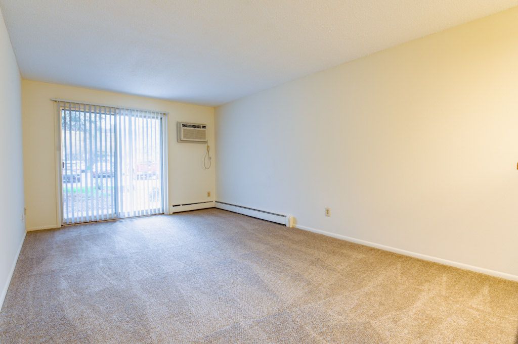 An empty living room with a sliding glass door and a window.