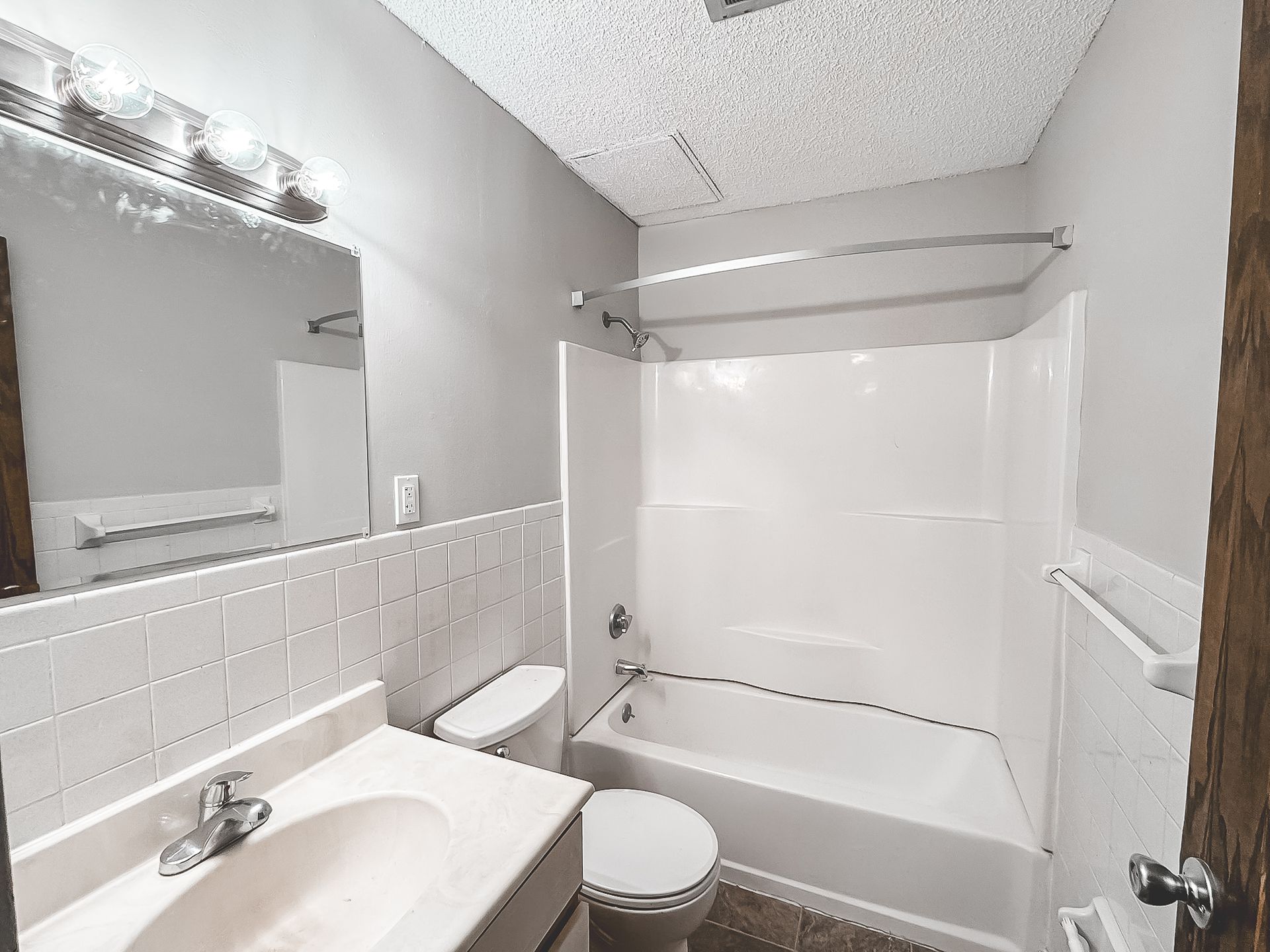 A bathroom with a toilet , sink , tub and mirror.
