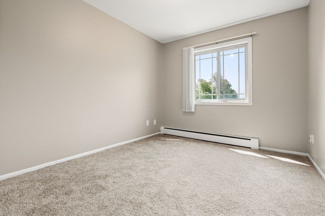 An empty bedroom with a window and a radiator.