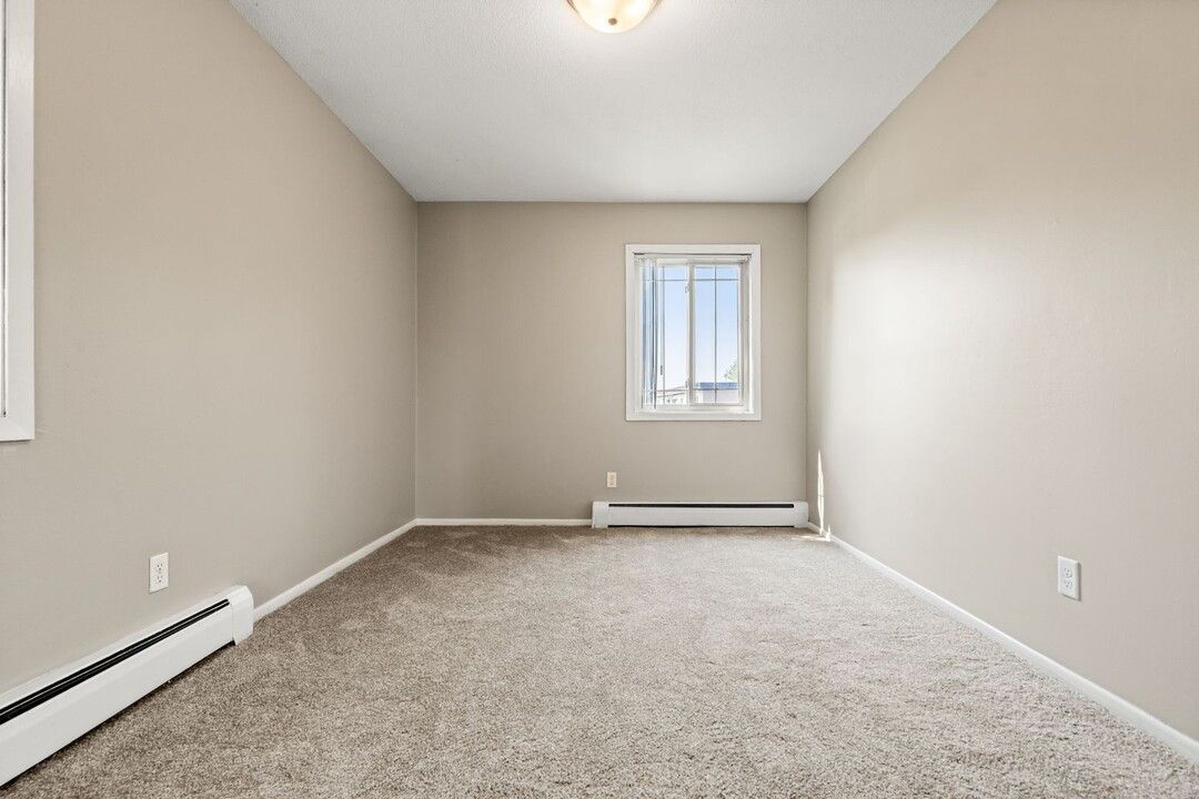An empty room with a window and a carpeted floor.