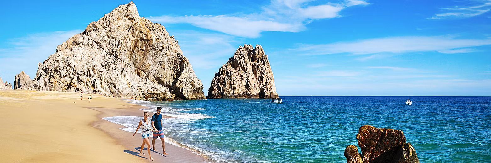 A couple is standing on a beach near the ocean.