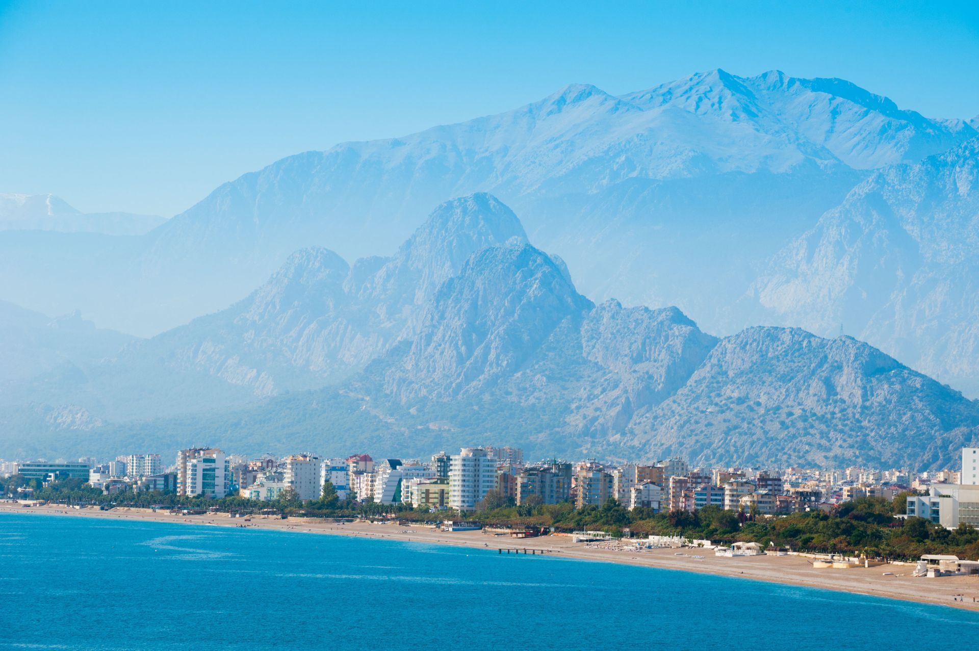 Aerial view of Konyaaltı Plajları, a beach in Antalya, Turkey with big mountains in the background.