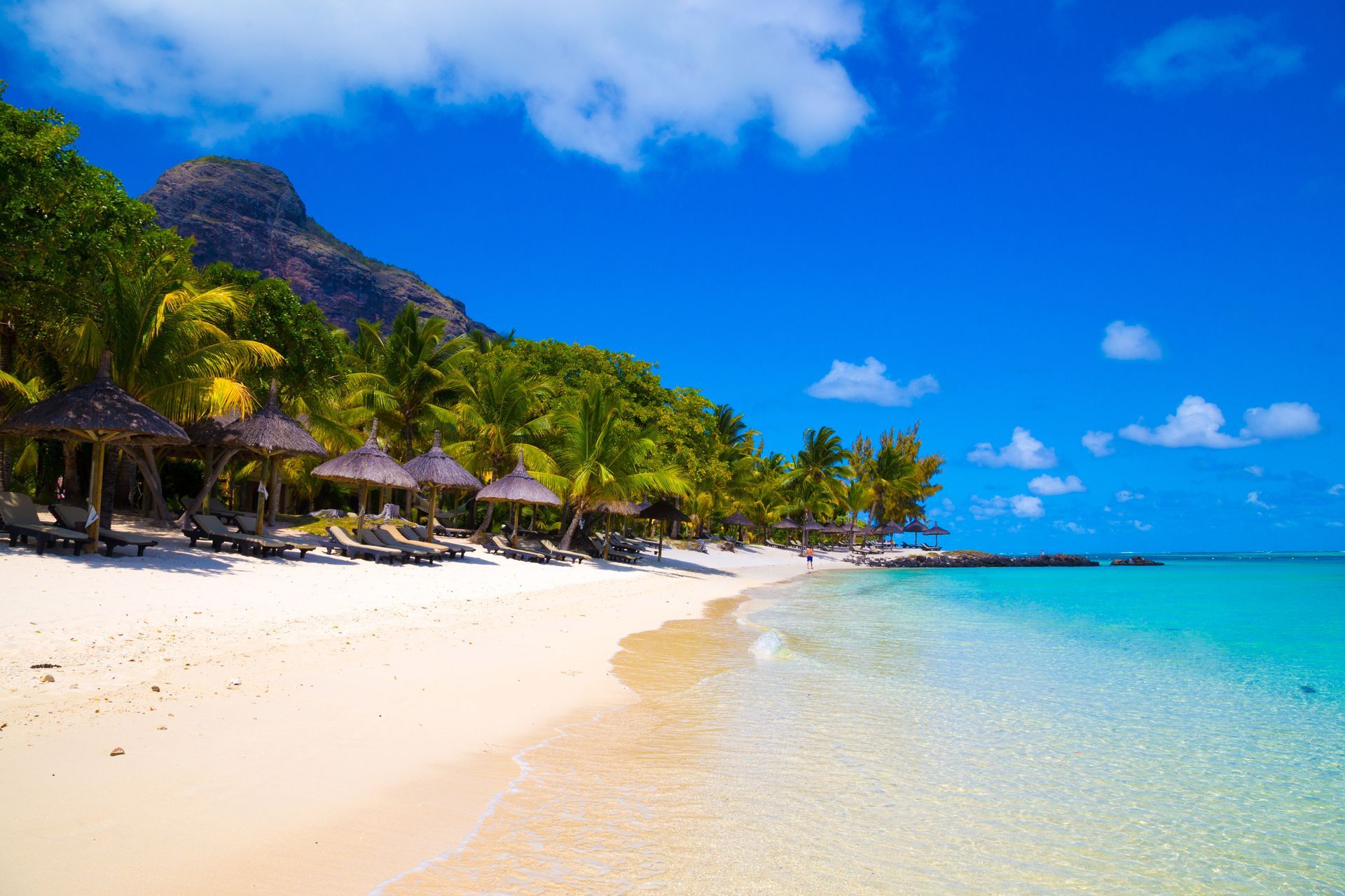 Tanning bed and beach umbrella facing the tropical lagoon, Le Morne Brabant in Mauritius, Indian Ocean.