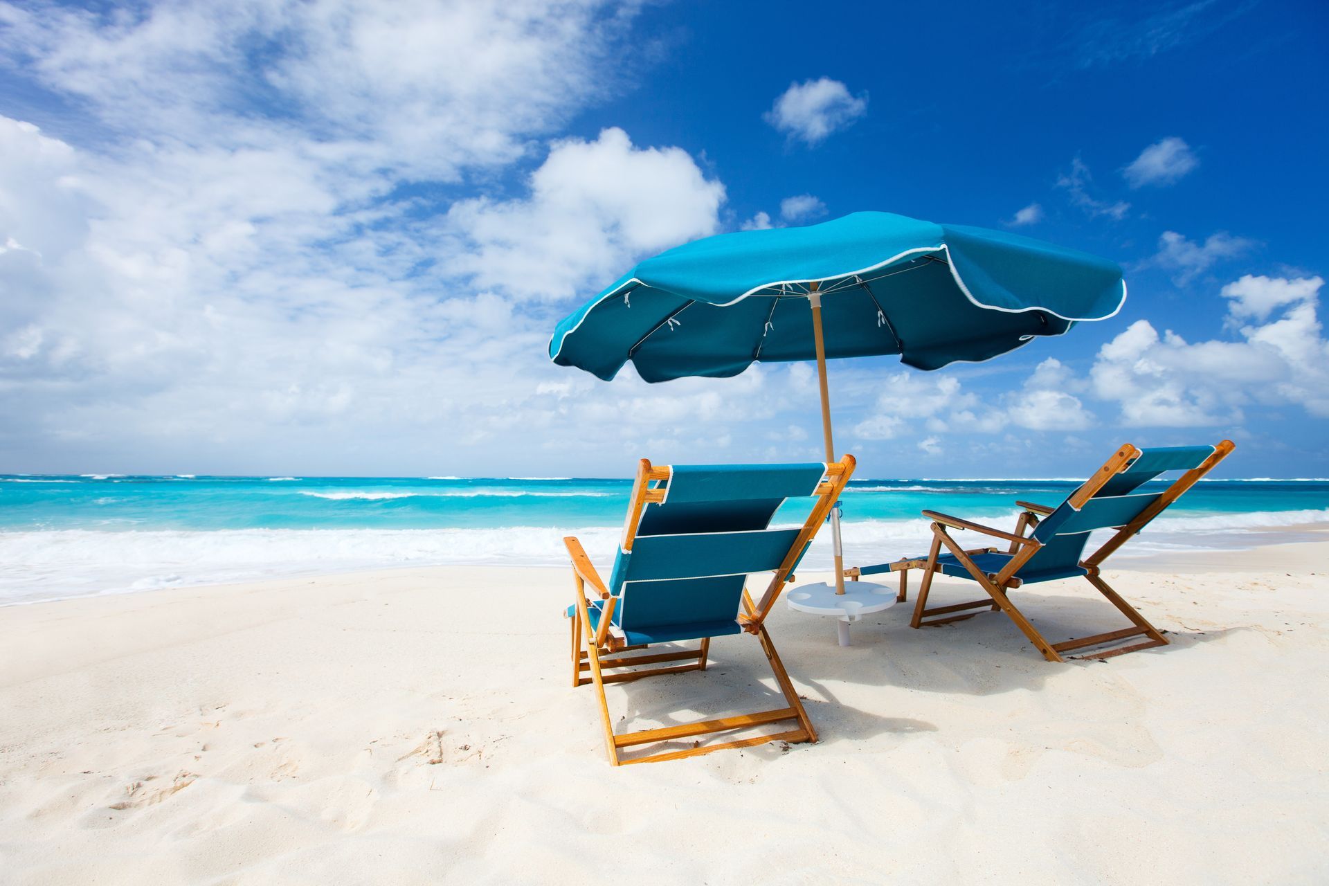 Beautiful beach with an umbrella and chairs on the sand.