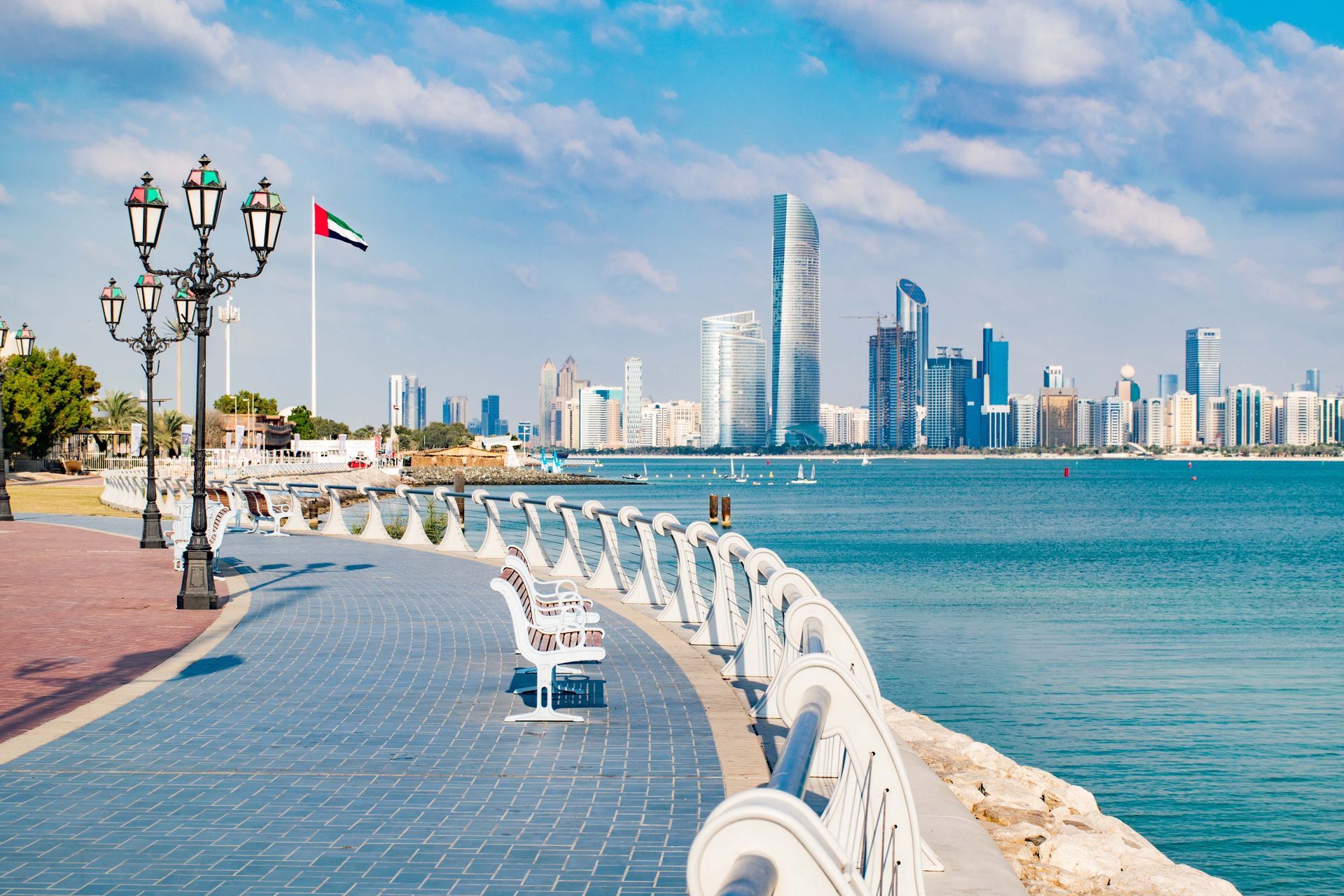 A walkway along the water with a city skyline in the background.