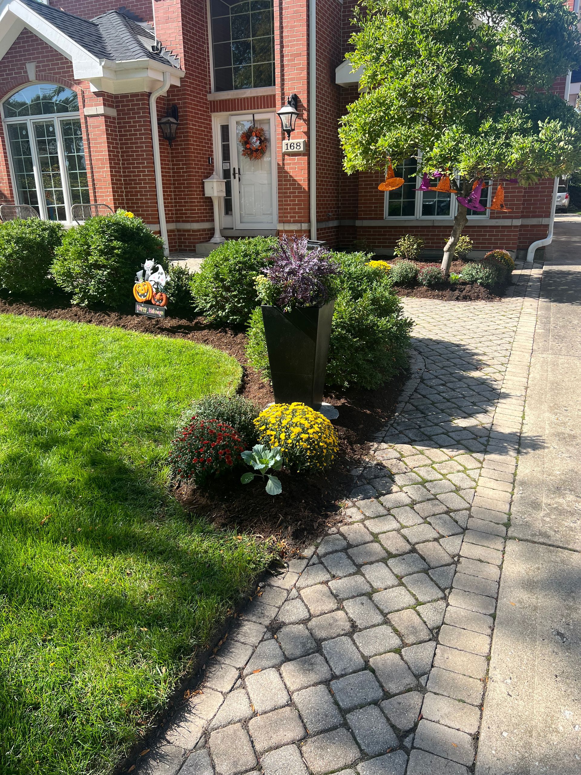 Brick home with flower beds, a brick pathway, and a grassy lawn.