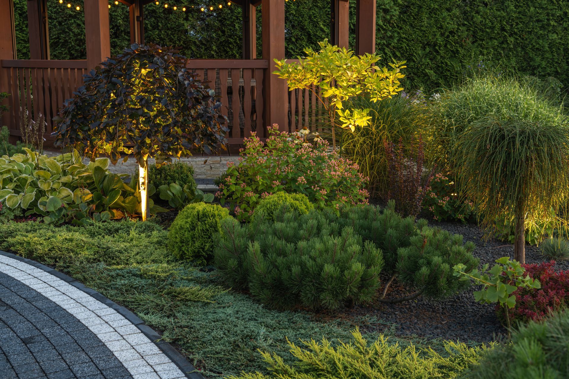 A garden with lots of plants and a gazebo in the background.