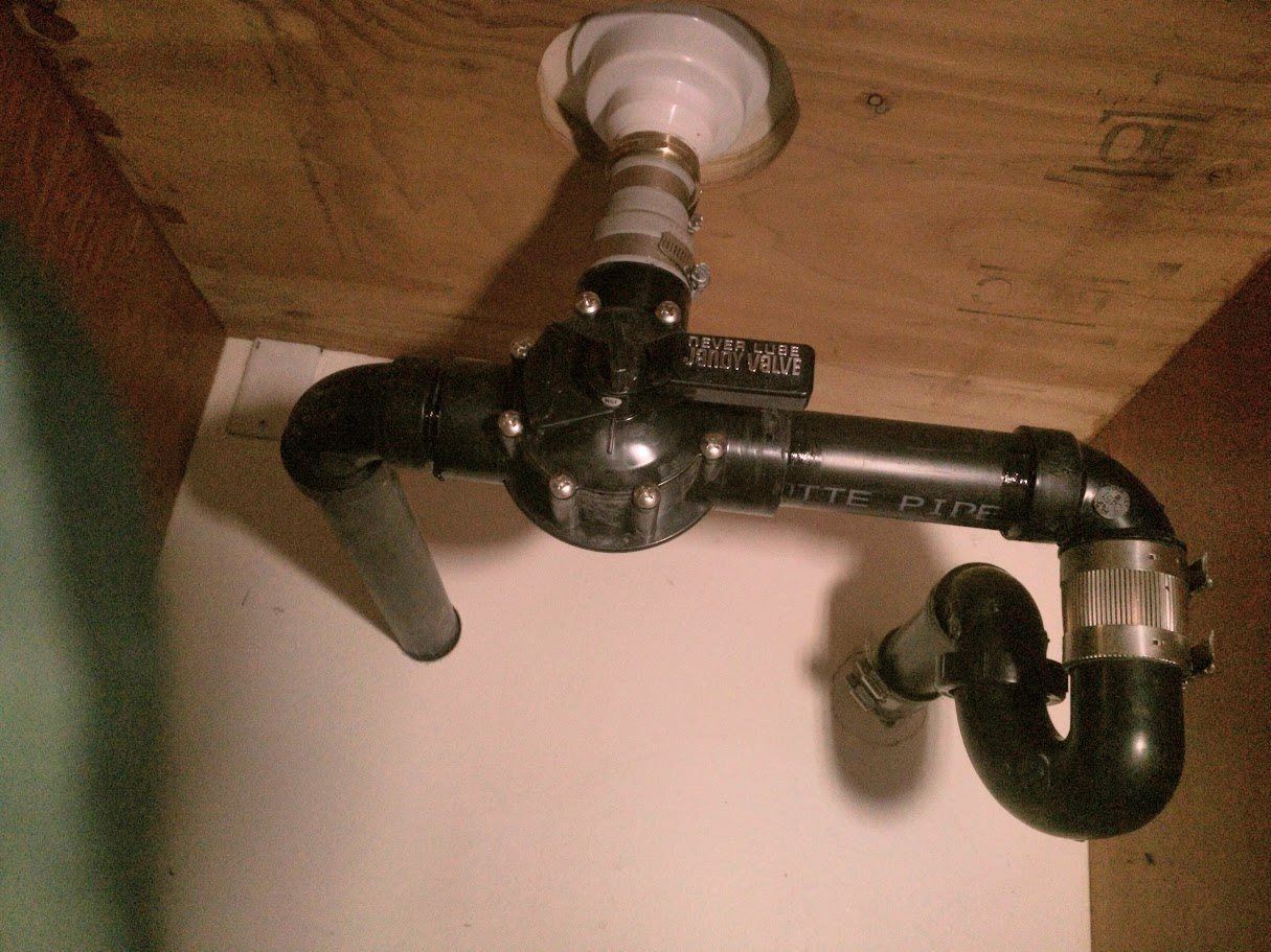 A black pipe is hanging from the ceiling under a sink.
