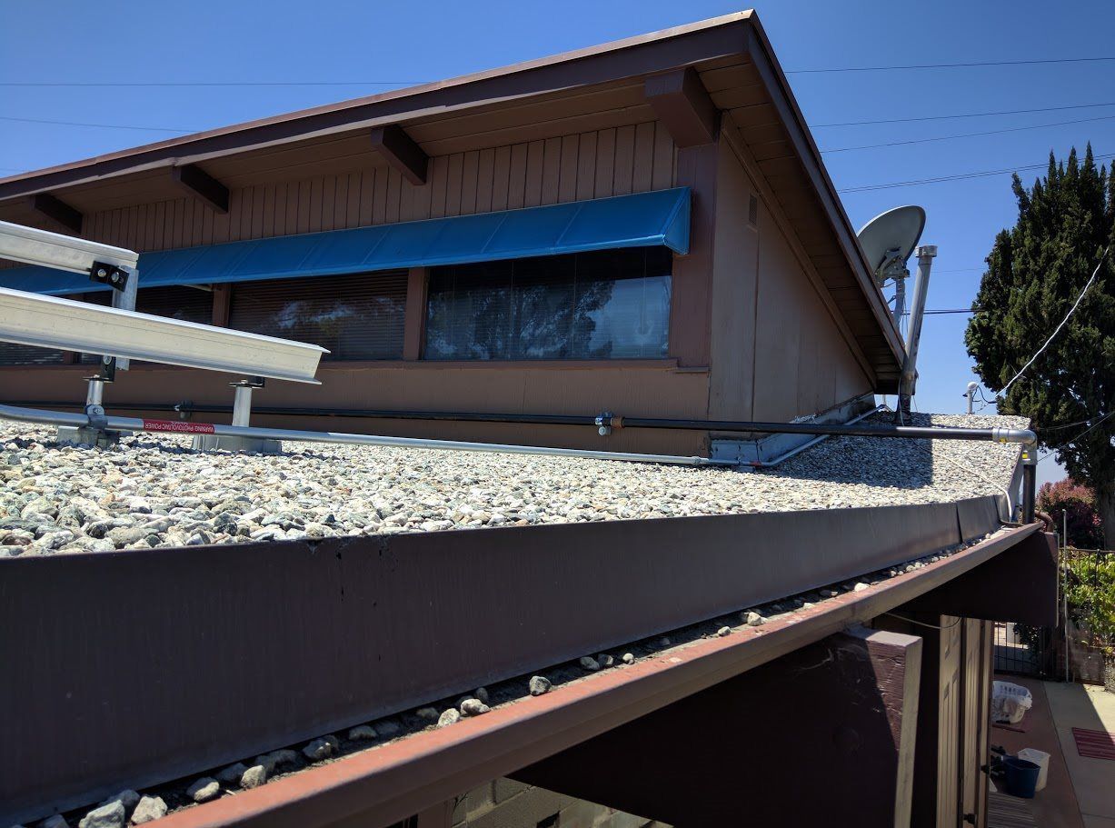 A house with a blue awning and a satellite dish on the roof.