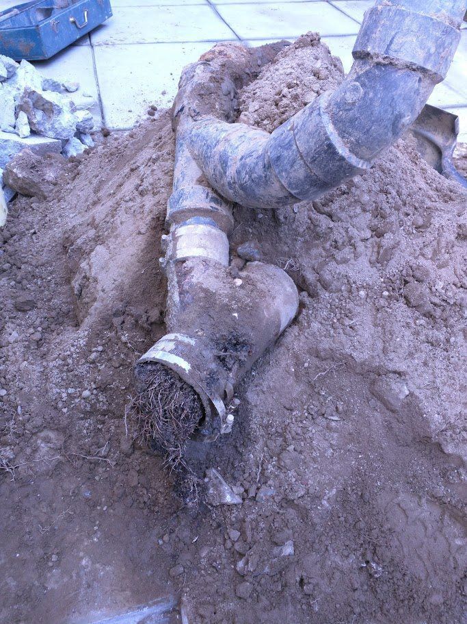 A pipe is laying in the dirt next to a pile of dirt.