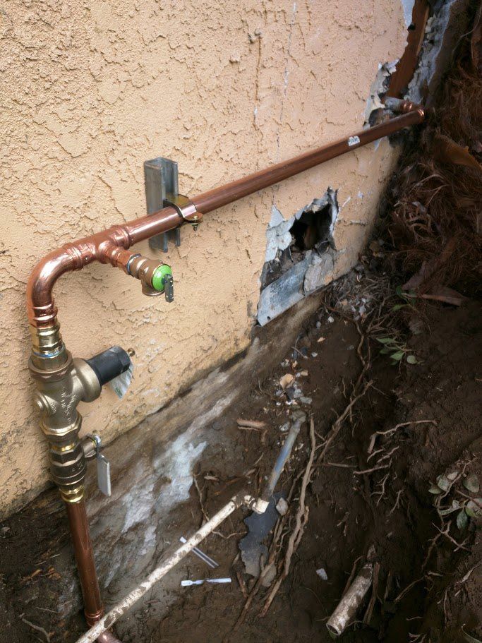 A copper pipe is attached to the side of a building