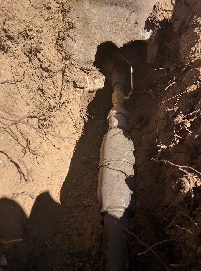A pipe is laying in the dirt in a hole.