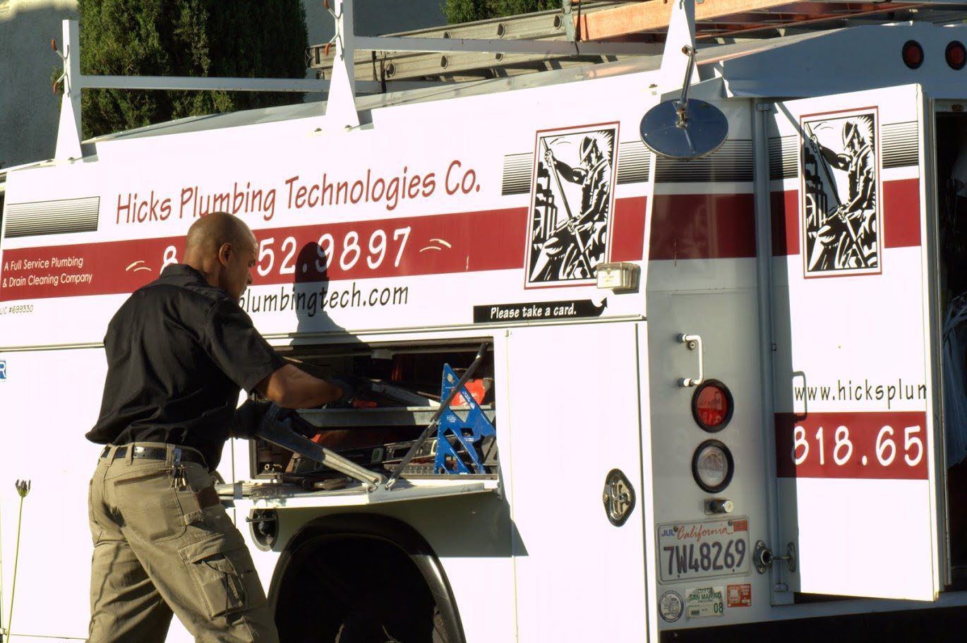 A man is working on a truck that says hicks floating technologies co.