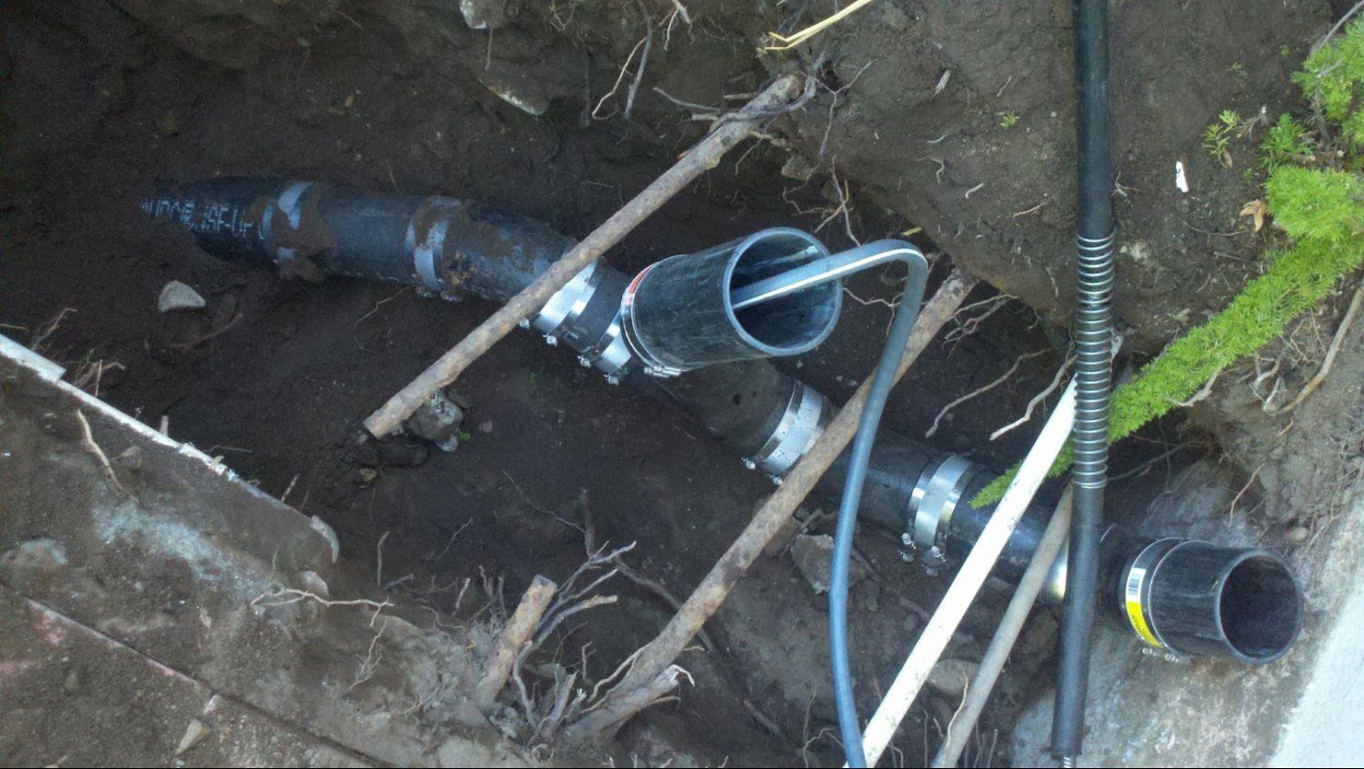A bunch of pipes are laying in the dirt.