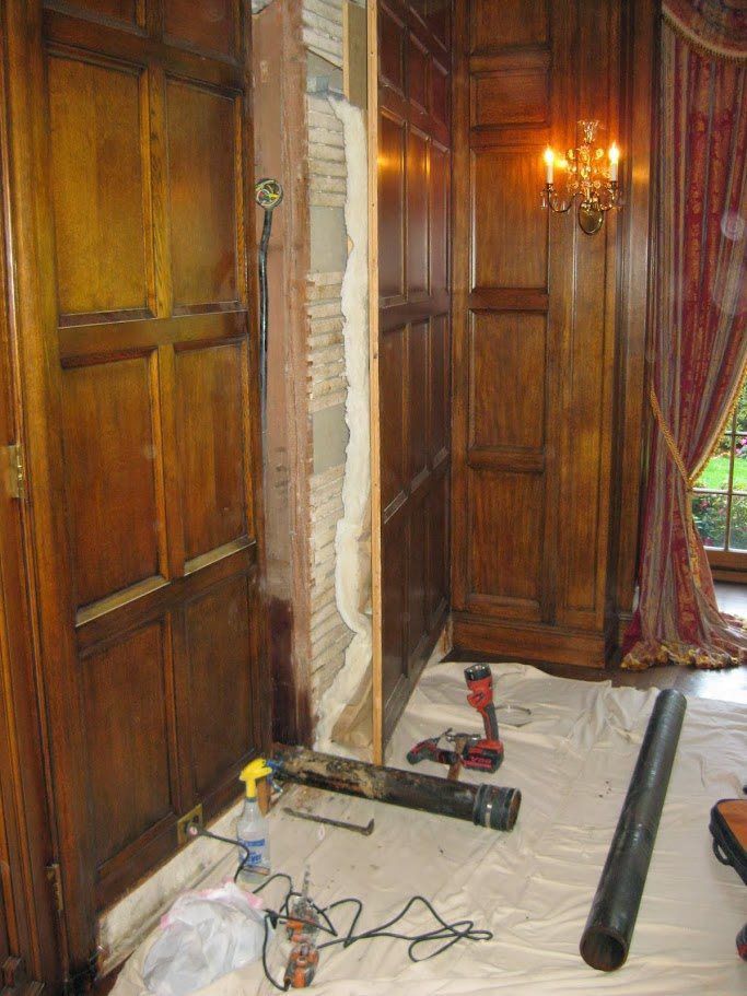 A room with wood paneling and a drill on the floor