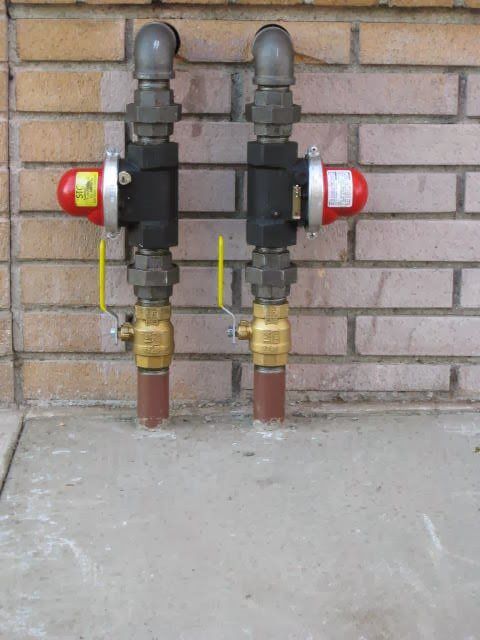 Two valves are attached to a brick wall