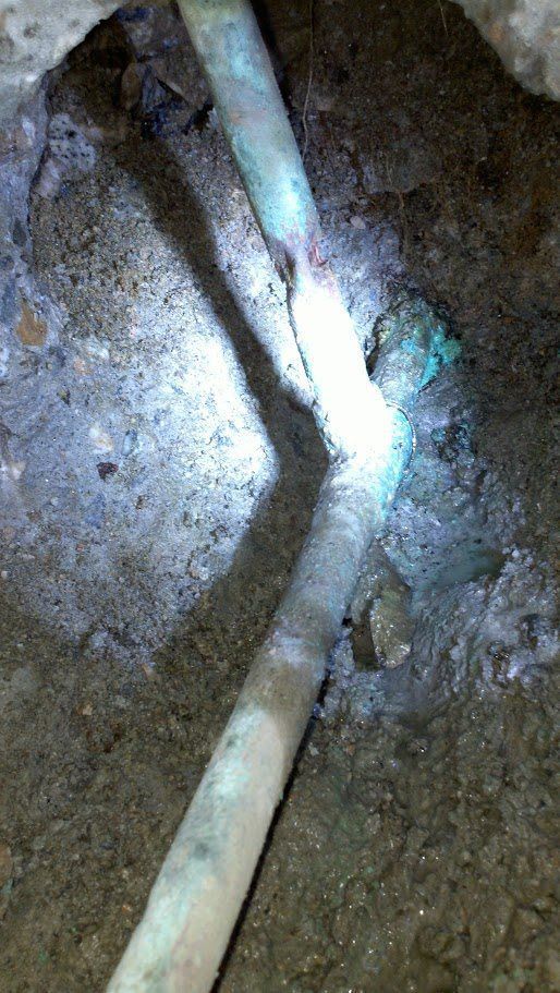 A close up of a pipe in the ground with a light shining on it.