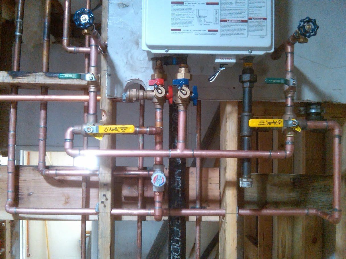 A bunch of copper pipes are connected to a water heater