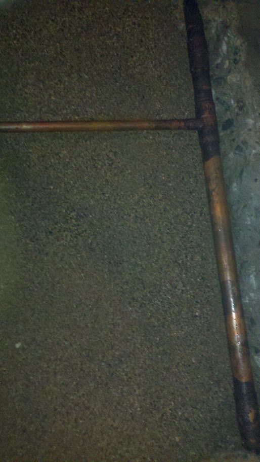 A copper rake is sitting on top of a pile of dirt.
